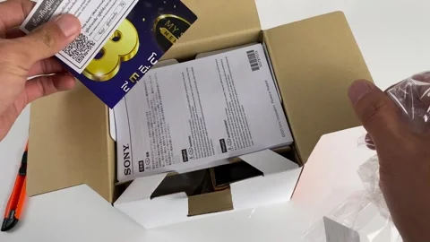 Hand unboxing Sony ZV-E10 camera box. Manual paper and camera in box. Stock Footage 250308347