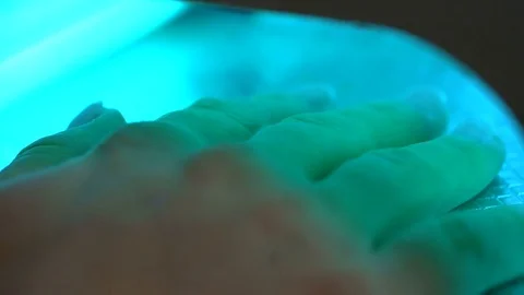 Hand under the lamp for polymerization of nails after extensions at beautician Stock Footage 84918515