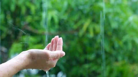Hand under the rain, rainwater close-up. Woman putting her hand out to feel r Stock Footage 87753778