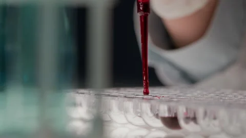 Hand of Unknown Chemist Dispensing Red Solution from Dropper into Wells Stockbeeldmateriaal 307938399