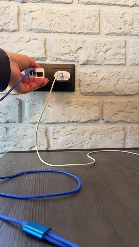 The hand of an unknown person inserts a power supply with a display from a power Vidéo 316805725