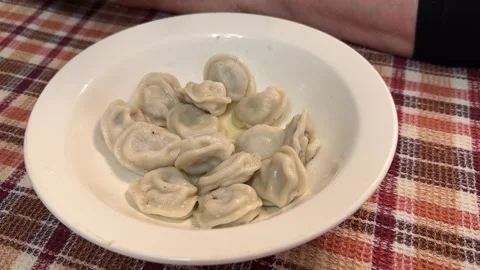 The hand of an unknown person picks up and stirs dumplings from a white plate Video stock 271412345