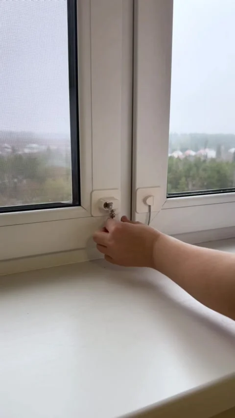 Hand unlocking child safety window blocker with key and opening plastic window Stock Footage 321757293