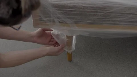 Hand unpackages plastic wrap from new couch midcentury Stock Footage 246057032