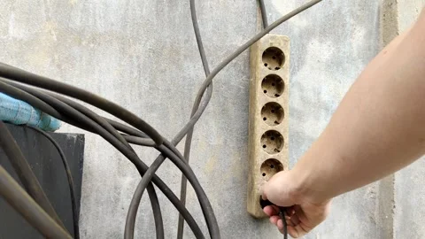 Hand Unplugging Cable Into Old Power Strip Outdoors on Concrete Wall Stock Footage 305037011