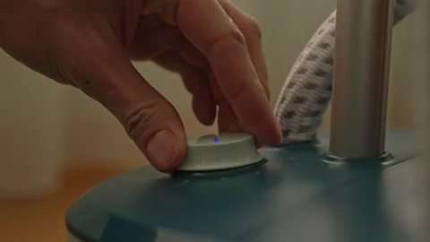 Hand of unrecognizable man turning white knob on clothes steamer to adjust steam Stock Footage 304858658