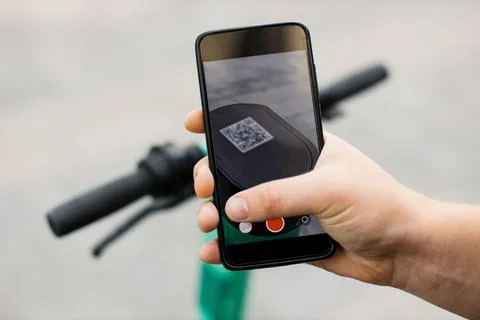 Hand of unrecognizable man using smartphone for renting modern electric scooter Stock Photos
