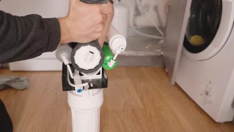 Hand Unscrewing the Lid of a Reverse Osmosis System to Access and Remove the Old Stock Footage 296571963