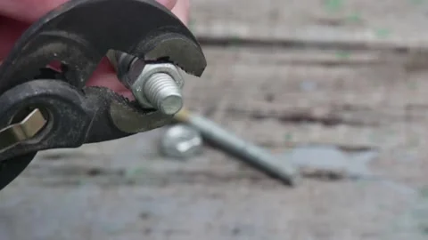 A hand unwinds a bolt from a nut holding with an adjustable wrench, close-up Vídeos de archivo 224991014