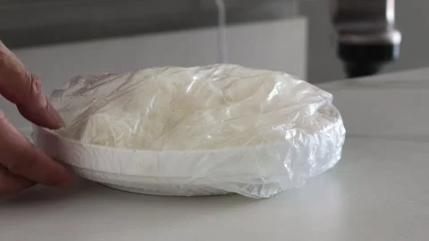Hand Unwrapping Plastic Wrap From Rice Plate On Kitchen Counter Vídeos de archivo 343369448