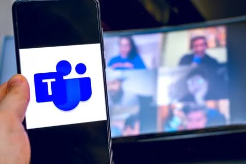 Hand use videoconference app icon of Microsoft Teams on smartphone. Stock Photos