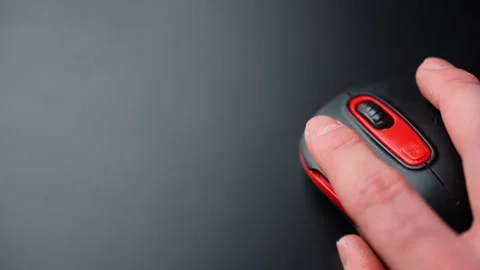 Hand uses a black and red wireless mouse on a dark desk with large copy space 스톡 동영상 328974832