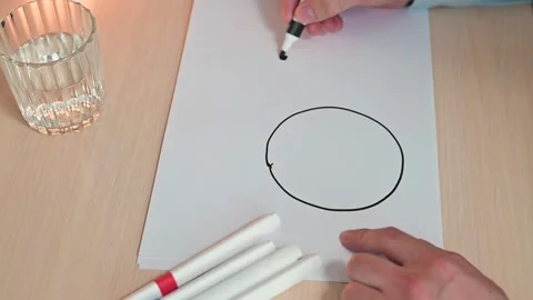 A hand uses a black marker to draw a circle on paper. The movement is Stock Footage 337558706
