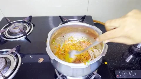 Hand uses ladle to blend paste mixture gently over flame Stock Footage 313277231