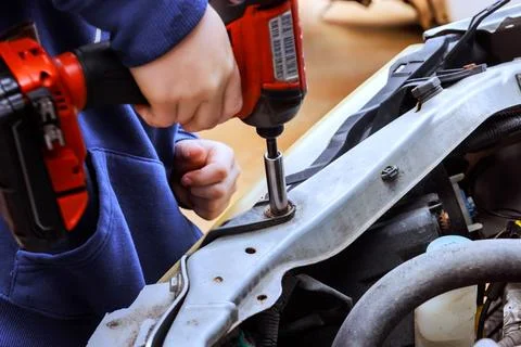 Hand uses power tool to fix part in car engine at garage 스톡 사진