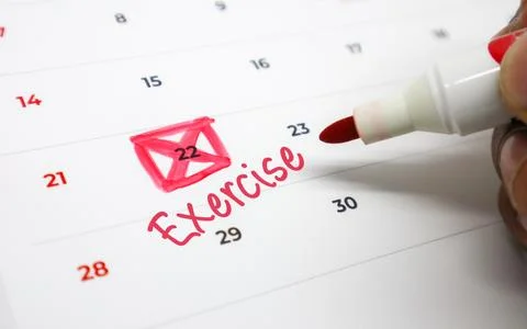 A hand uses a red marker to highlight Exercise on a calendar, symbolizing a.. Stock Photos