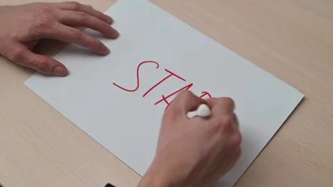 A hand uses a red marker to write the word start on a piece of white paper. The 스톡 동영상 337550451