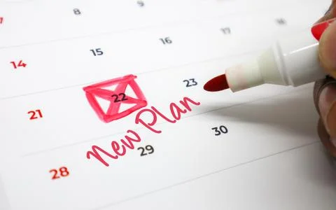 Hand uses a red marker to write New Plan on a calendar, highlighting a crit.. Stock Photos