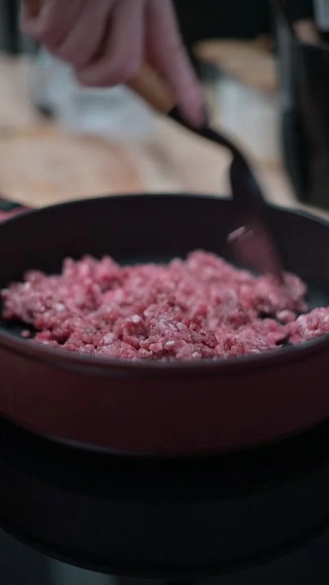 A hand uses a spatula to stir and break apart ground meat in a skillet on the 库存影片 337112342