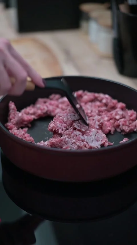 A hand uses a spatula to stir and break apart ground meat in a frying pan. This 库存影片 337112344