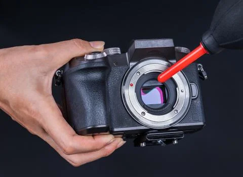 Hand using air blower to cleaning dust on camera sensor Stock Photos