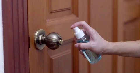 Hand using alcohol sanitizer spray cleansing on doorknob Stock Footage 129600870