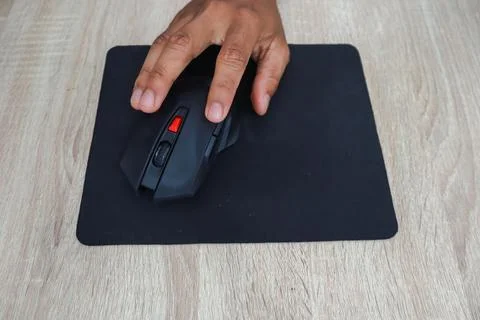 Hand Using Black Ergonomic Computer Mouse On Wooden Desk Foto stock