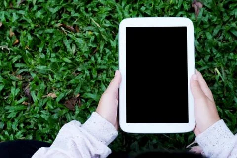 Hand using blank screen tablet over green grasses background, mock up, busine Stock Photos