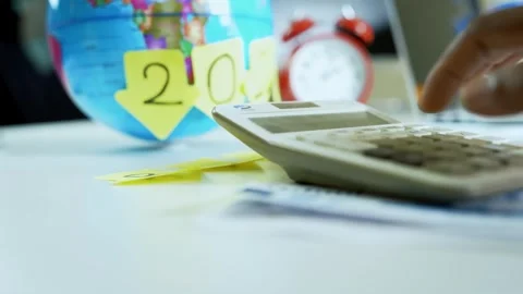 Hand Using Calculator with Globe and Sticky Notes Stock Footage 321223961