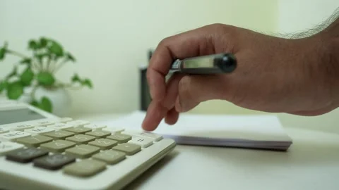 Hand Using Calculator with Pen on Desk, Close-up of a hand using a calculat.. Stock Footage 317737436