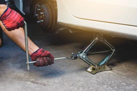 Hand using car jack for lifting tire emergency change. Foto stock