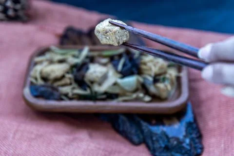 The hand is using chopsticks to pick up Stir-fried tofu with ginger in wooden Stock Photos