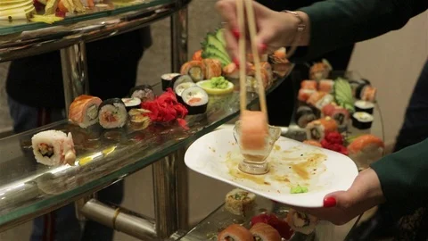Hand using chopsticks pick Sushi and Sashimi rolls on the glass table. Video stock 97074943
