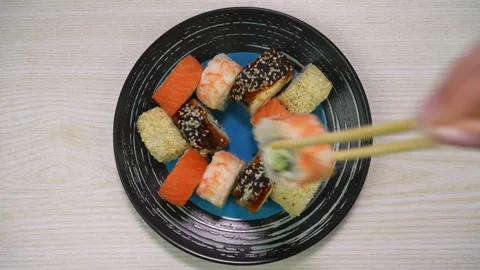 Hand using chopsticks to pick up a sushi roll off of a platter Stock-Footage 313002039