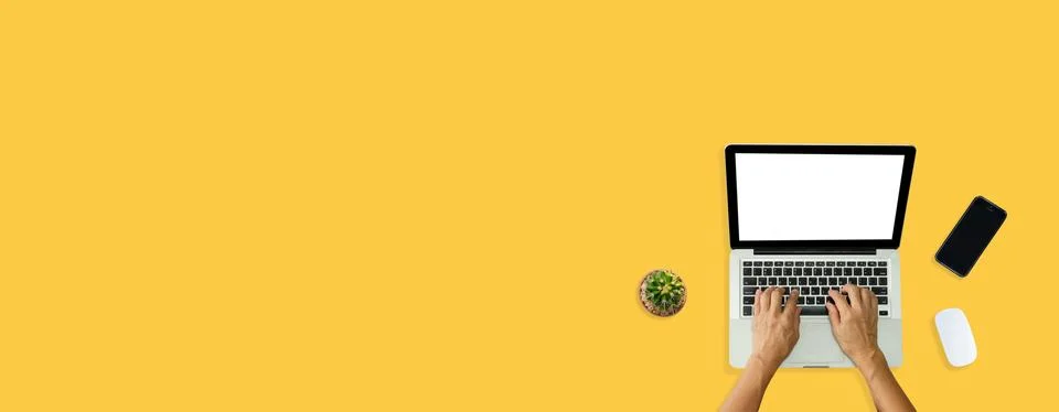 Hand using computer laptop and mouse, phone from above on yellow background. Stock Photos