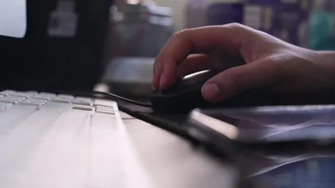 Hand Using Computer Mouse Beside Keyboard and Smartphone on Office Desk Stock Footage 333857060