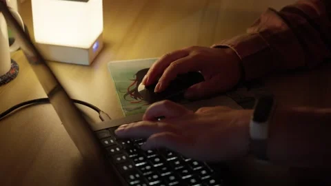 Hand Using Computer Mouse Beside Laptop in Warm Home Workspace Stock Footage 344948093