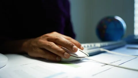 Hand using computer mouse beside plans and globe, Close-up of a hand using .. Video stock 346462254