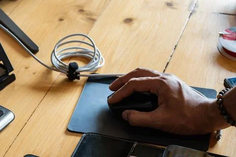 A hand using a computer mouse on a wooden desk, highlighting everyday compu.. Stock Photos