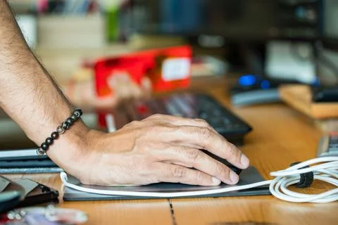 A hand using a computer mouse on a wooden desk, highlighting everyday compu.. Stock Photos