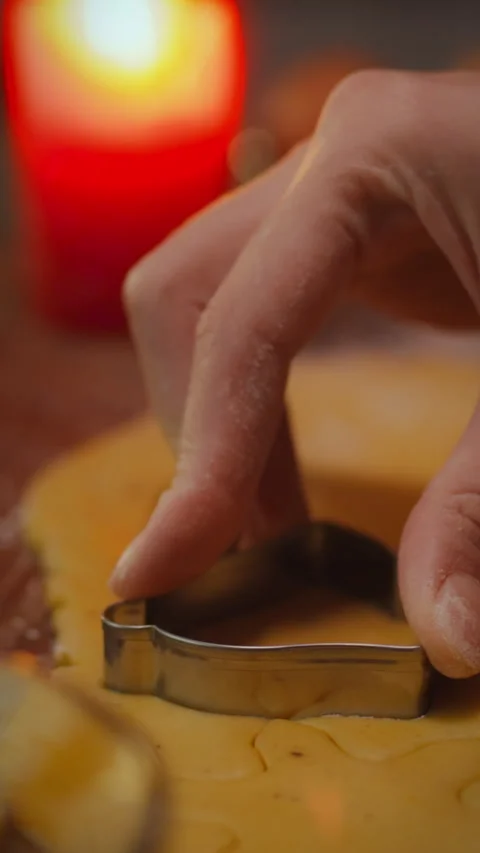 Hand using a cookie cutter to shape dough during evening baking activity Stock Footage 331596643