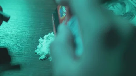 Hand using credit card to chop cocaine. Green light Stock Footage 74970239