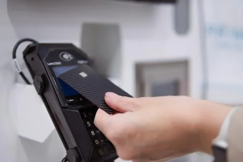 Hand using a credit card with dynamic carbon fiber texture for a contactles.. Stock Photos