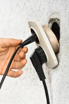 Hand using dangerous broken electric socket Stock Photos
