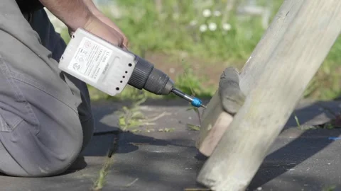 Hand using electric screwdriver to drive a screw into a board Stock Footage 302294838