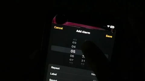 Hand using a finger to scroll and adjust the time setting on a smartphone Stock Footage 339304772