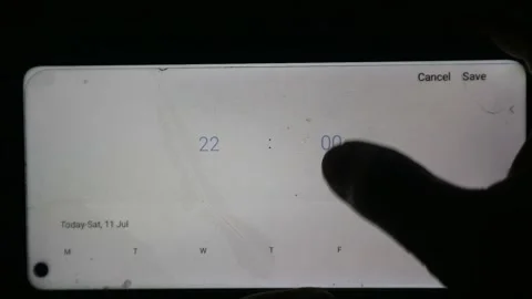 Hand using a finger to scroll and adjust the time setting on a smartphone Stock Footage 339304792