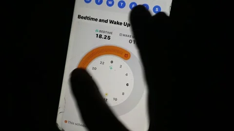 Hand using a finger to scroll and adjust the time setting on a smartphone Stock Footage 339304795