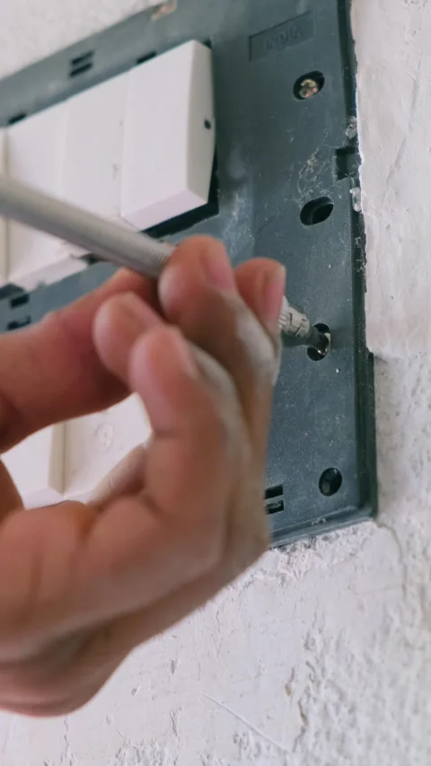 Hand using a flexible screwdriver to unscrew a modular switchboard frame 스톡 동영상 332998052