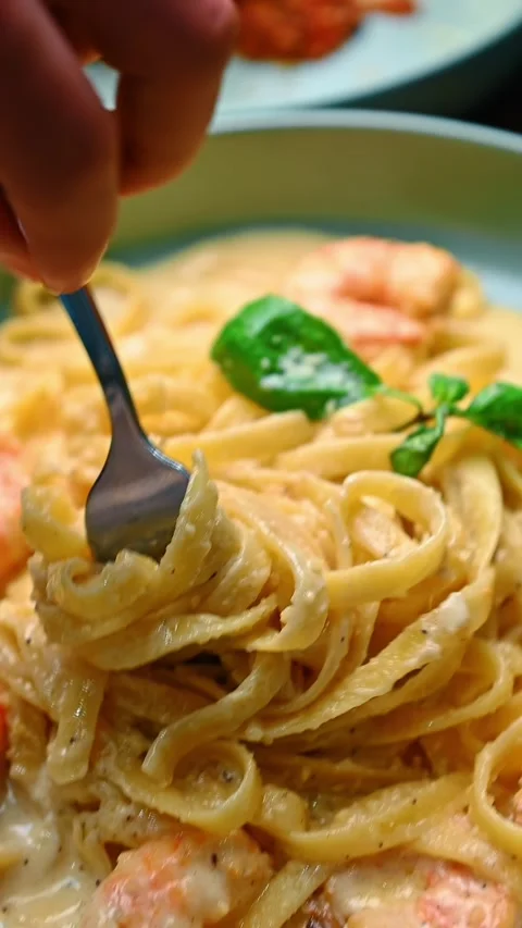 Hand using fork to eat creamy shrimp pasta. Action shot of hand lifting Stock-Footage 329511279
